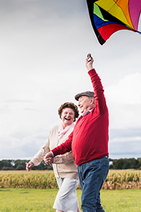 A family enjoys a summer day in a grassy field, the sky filled with kites as a woman and child share in the fun.