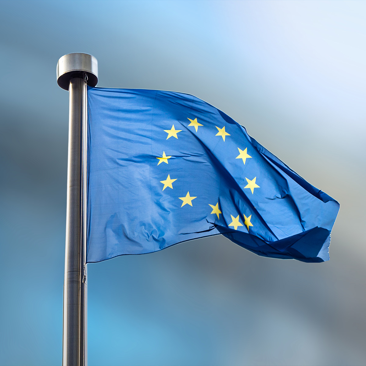 Le drapeau de l'Union Européenne, orné d'étoiles, flotte contre le ciel bleu vibrant, symbolisant l'unité en Europe.